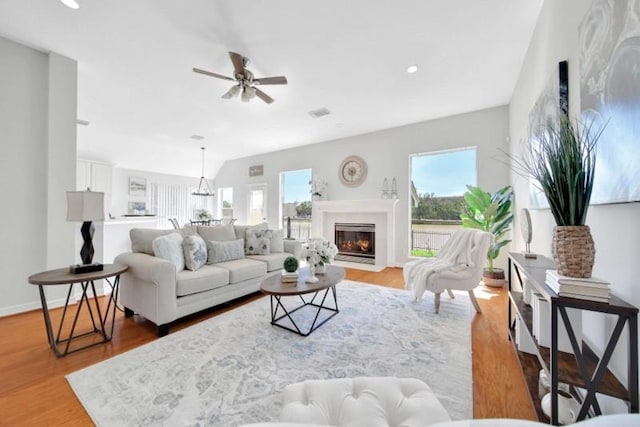 living room featuring a healthy amount of sunlight, a fireplace with flush hearth, baseboards, and light wood-style flooring