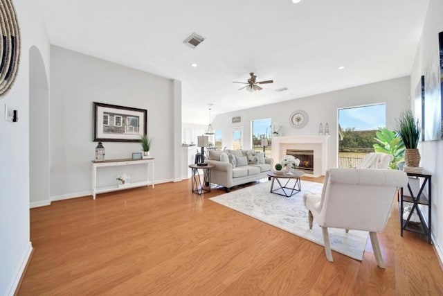 living room with a healthy amount of sunlight, light wood-type flooring, a fireplace with flush hearth, and visible vents