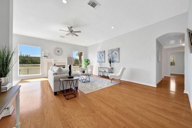 living room with arched walkways, wood finished floors, visible vents, and a healthy amount of sunlight