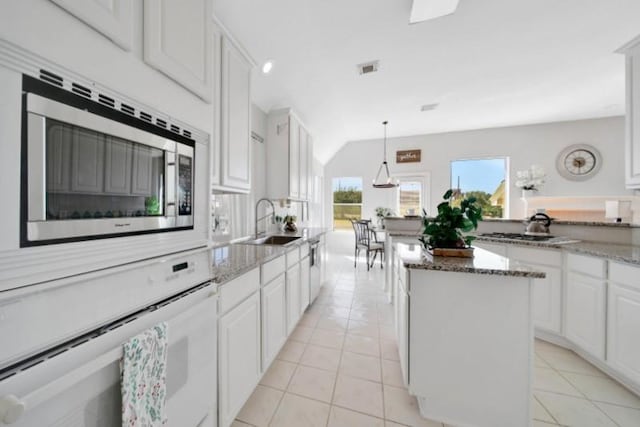 kitchen with light tile patterned floors, stainless steel microwave, a kitchen island, and oven