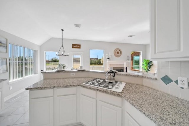 kitchen with light stone counters, a fireplace, visible vents, decorative backsplash, and white gas cooktop