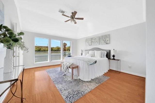 bedroom featuring baseboards, visible vents, a ceiling fan, wood finished floors, and vaulted ceiling