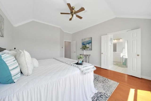 bedroom with lofted ceiling, baseboards, wood finished floors, and ensuite bathroom