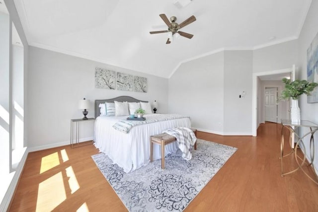 bedroom with crown molding, baseboards, vaulted ceiling, and wood finished floors