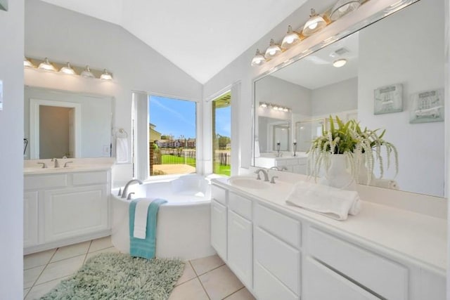 full bathroom featuring two vanities, tile patterned floors, a sink, vaulted ceiling, and a bath