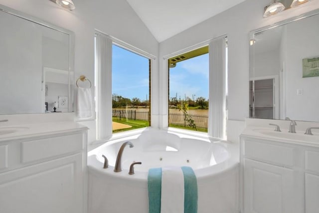 bathroom with a jetted tub, vaulted ceiling, and vanity