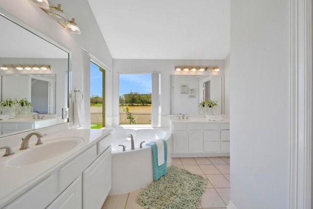 full bathroom featuring tile patterned floors, two vanities, vaulted ceiling, a sink, and a bath