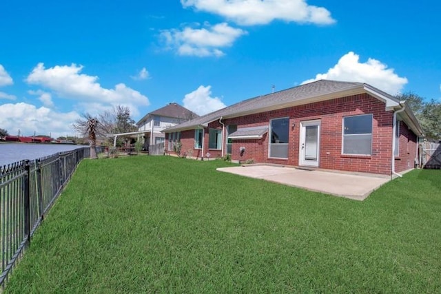 back of property with a yard, a patio, brick siding, and a water view