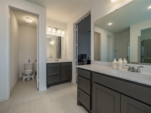 full bath with a sink, visible vents, toilet, and two vanities