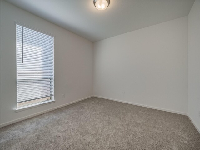 carpeted spare room featuring baseboards