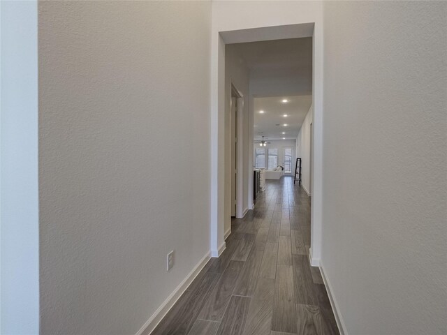 hallway featuring dark wood finished floors and baseboards