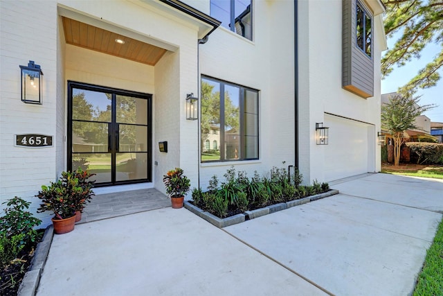 view of exterior entry featuring brick siding, driveway, and an attached garage