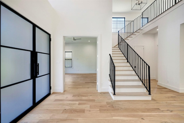 staircase with baseboards, a high ceiling, wood finished floors, and a ceiling fan