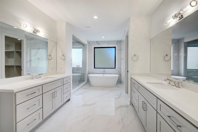 full bathroom featuring a sink, a soaking tub, marble finish floor, and two vanities