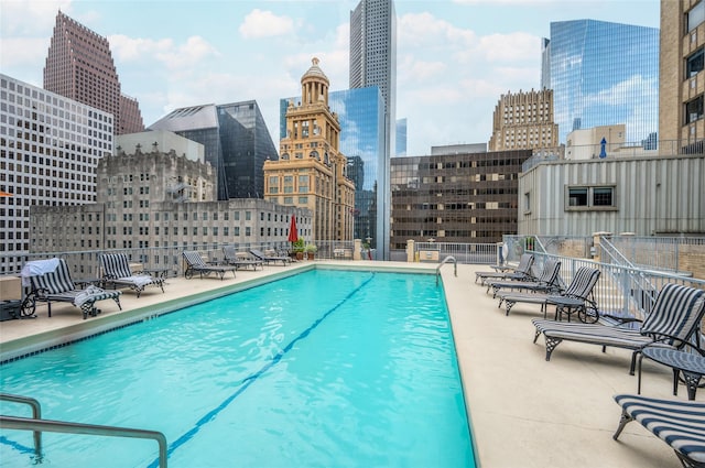 community pool featuring a patio area, a city view, and fence