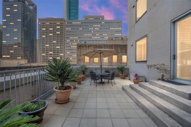 patio terrace at dusk featuring outdoor dining space and a view of city