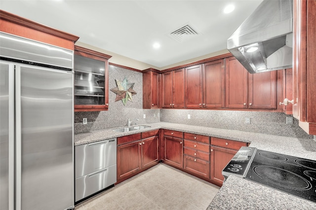 kitchen featuring visible vents, decorative backsplash, stainless steel appliances, wall chimney exhaust hood, and a sink