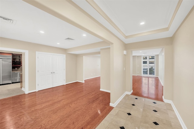 corridor featuring visible vents, baseboards, and light wood finished floors