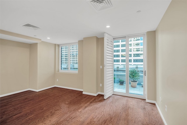 empty room featuring visible vents, baseboards, and wood finished floors