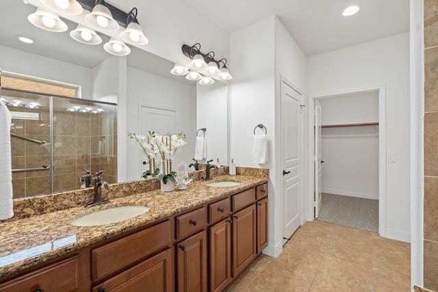 full bath featuring a sink, a walk in closet, a stall shower, and double vanity