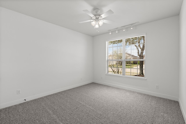 carpeted empty room featuring baseboards, track lighting, and a ceiling fan