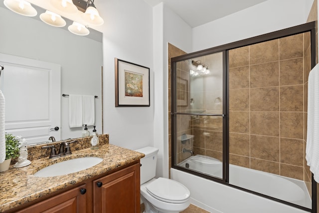 bathroom with toilet, vanity, and bath / shower combo with glass door