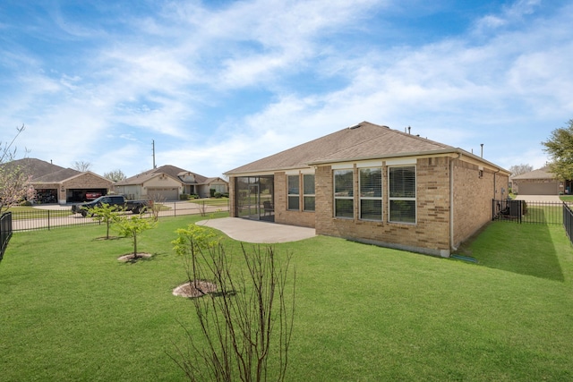 rear view of property featuring roof with shingles, brick siding, a fenced backyard, a patio area, and a lawn