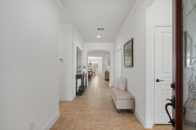 hall featuring crown molding, arched walkways, visible vents, and baseboards