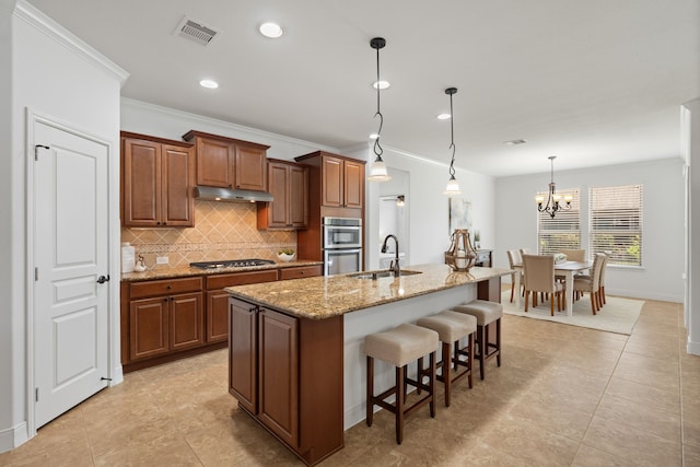 kitchen featuring visible vents, under cabinet range hood, a breakfast bar, stainless steel appliances, and a sink