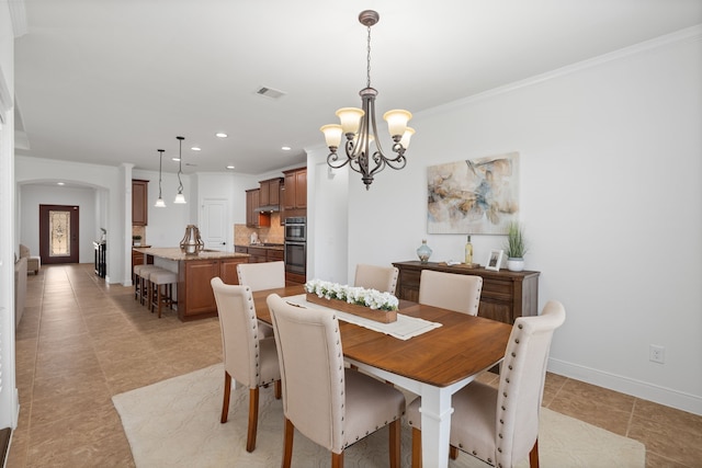 dining room with baseboards, visible vents, arched walkways, crown molding, and a chandelier