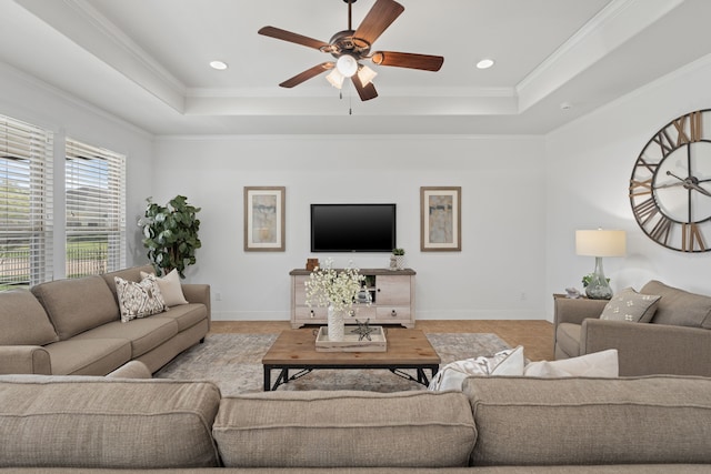 living area with baseboards, a raised ceiling, ceiling fan, and crown molding