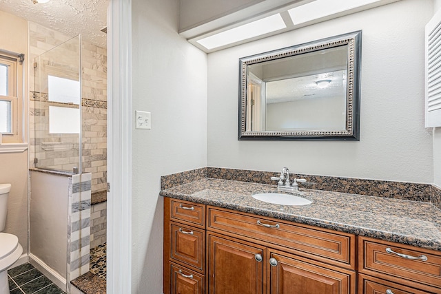 bathroom featuring vanity, a stall shower, tile patterned flooring, a textured ceiling, and toilet