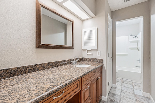 full bath featuring visible vents, baseboards, bathtub / shower combination, vanity, and a textured wall