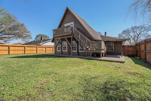 rear view of property featuring a wooden deck, a lawn, a fenced backyard, and brick siding