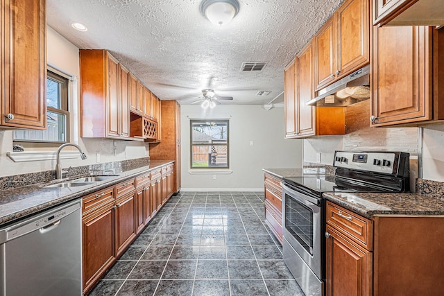 kitchen with brown cabinetry, visible vents, a sink, stainless steel appliances, and under cabinet range hood