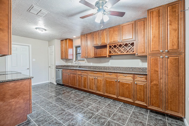 kitchen with visible vents, a sink, brown cabinetry, a ceiling fan, and stainless steel dishwasher