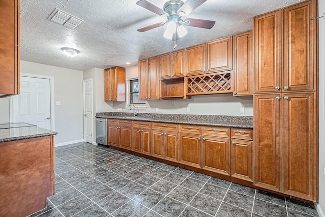 kitchen featuring a ceiling fan, visible vents, a sink, stainless steel dishwasher, and brown cabinets
