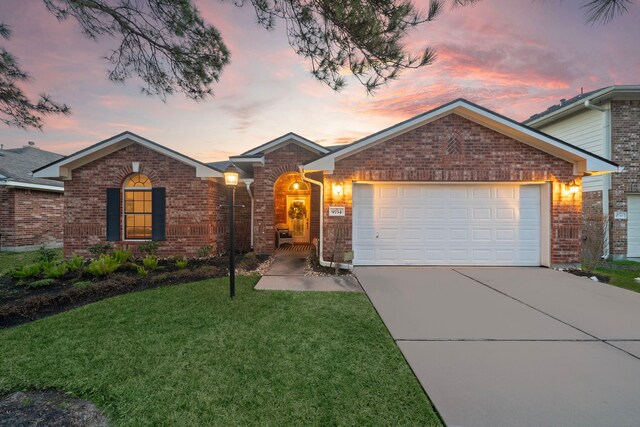 single story home with a garage, brick siding, a yard, and driveway