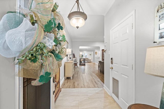 foyer featuring baseboards, light wood-style flooring, and crown molding