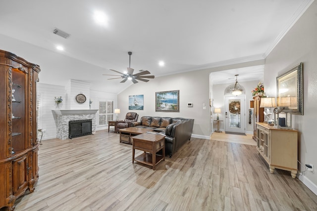 living room featuring lofted ceiling, light wood finished floors, a fireplace, and visible vents