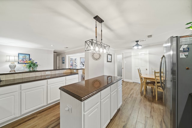 kitchen featuring light wood finished floors, visible vents, dark countertops, freestanding refrigerator, and white cabinetry