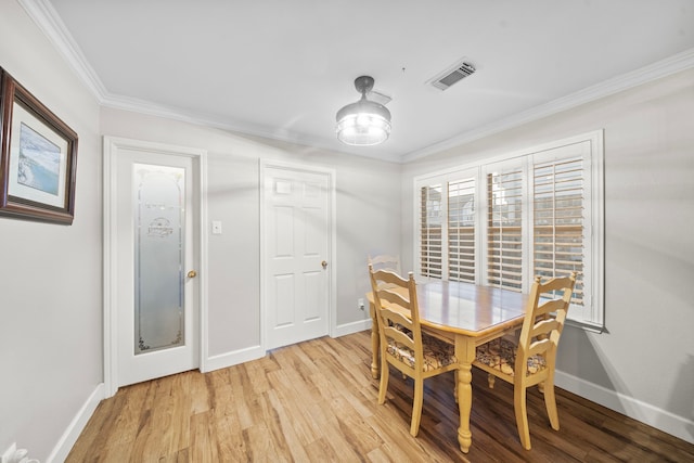 dining room with baseboards, ornamental molding, visible vents, and light wood-style floors