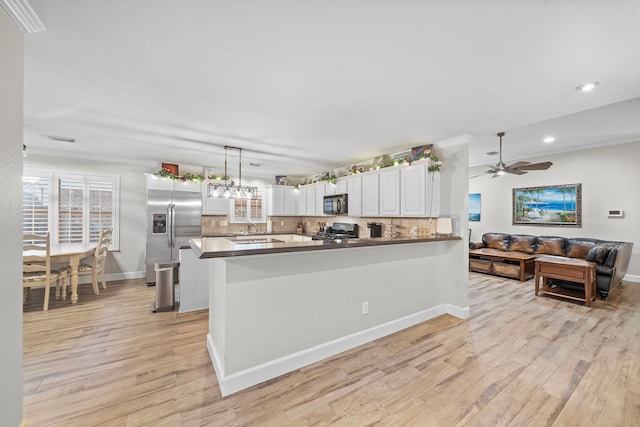 kitchen with gas range oven, black microwave, stainless steel refrigerator with ice dispenser, and backsplash