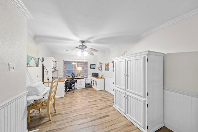 office area featuring a wainscoted wall, ornamental molding, light wood finished floors, and a ceiling fan