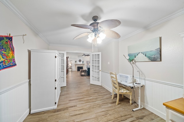 office space featuring light wood finished floors, wainscoting, ornamental molding, french doors, and a fireplace