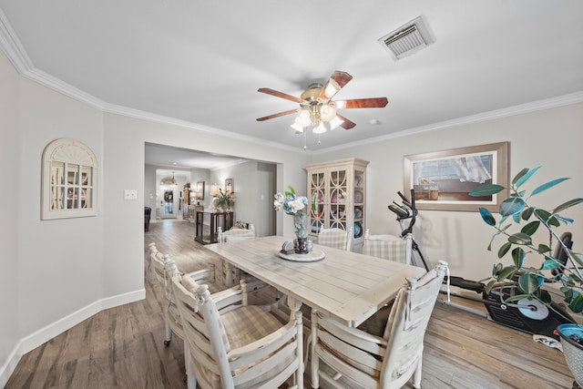 dining area with light wood-type flooring, baseboards, visible vents, and ornamental molding