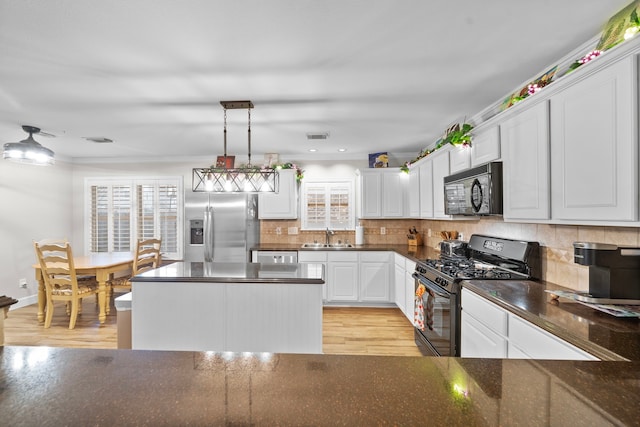 kitchen with light wood finished floors, decorative backsplash, white cabinetry, a sink, and black appliances