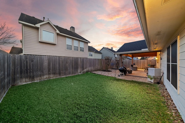 yard at dusk featuring a patio and a fenced backyard