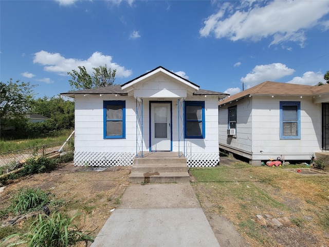 bungalow with entry steps, fence, and a front lawn