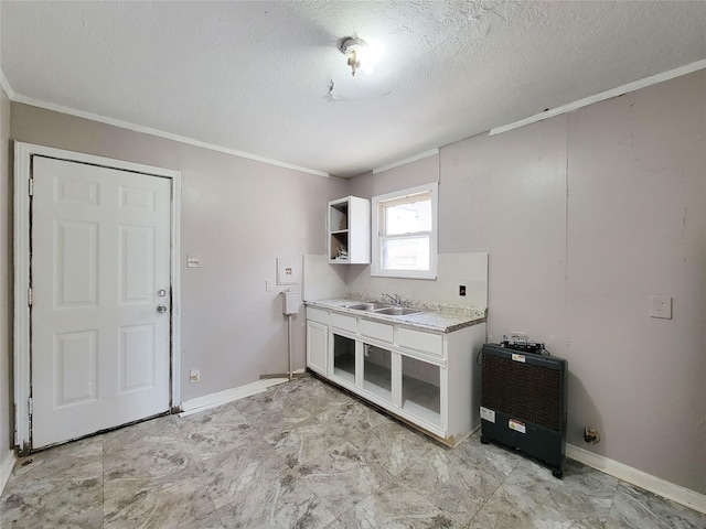 laundry area featuring a textured ceiling, crown molding, a sink, and baseboards